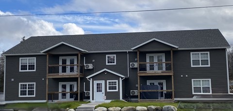 A grey two story house with a white door and windows.