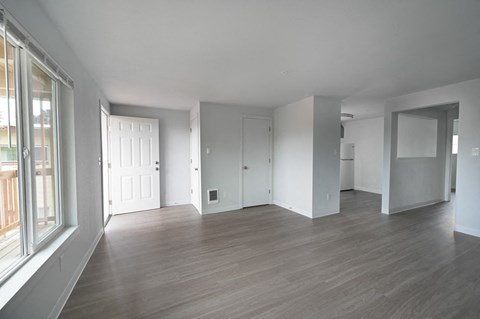 A spacious room with wooden flooring and white walls.