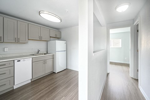 A kitchen with white appliances and wooden floors.