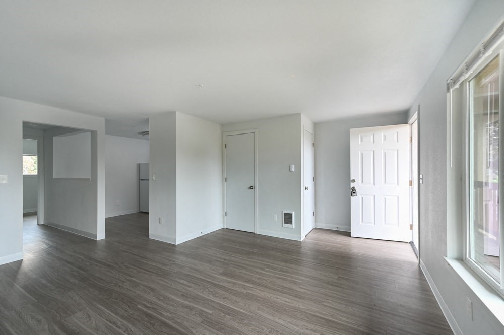 A spacious room with wooden floors and white walls.