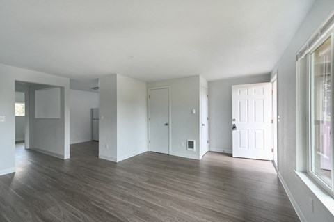 A spacious room with wooden floors and white walls.