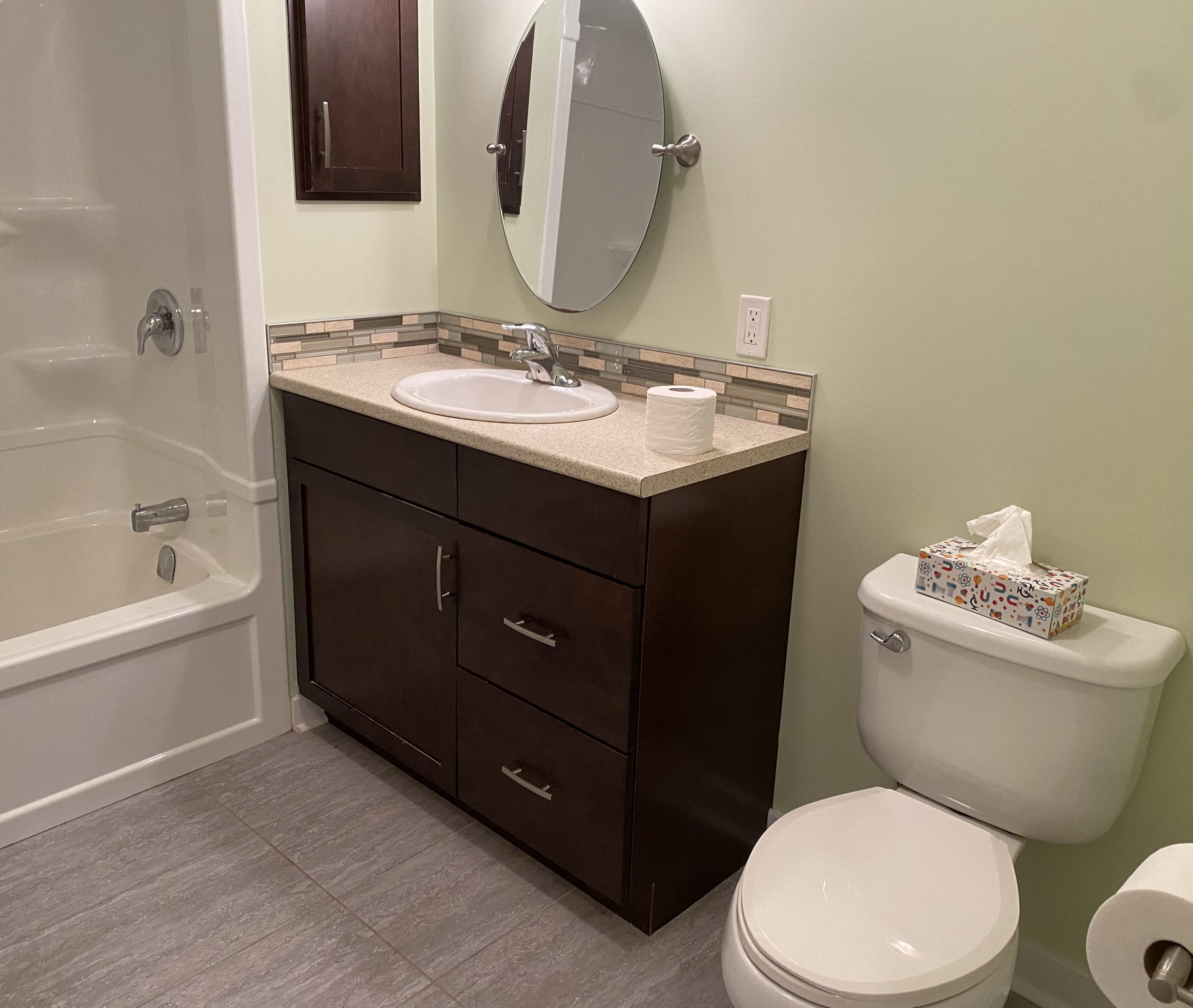 A bathroom with a toilet, sink, and mirror.