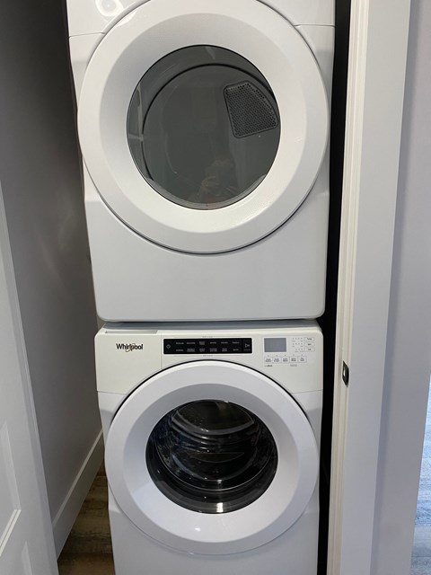 A white Whirlpool washing machine and dryer in a small laundry room.