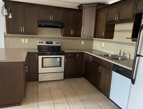 A kitchen with brown cabinets and a white stove top oven.