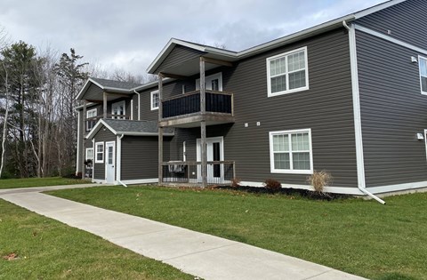 A grey two-story house with a balcony on the second floor.