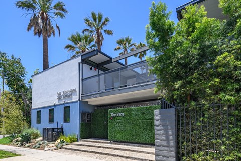 A modern house with a blue exterior and a green wall on the front.