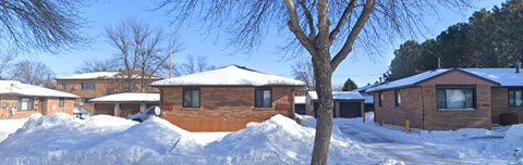 A house with a brown roof and a tree in front of it.