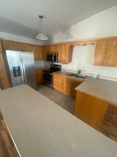 A kitchen with wooden cabinets and a stainless steel refrigerator.