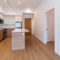 A kitchen with a white counter top and wooden floors.