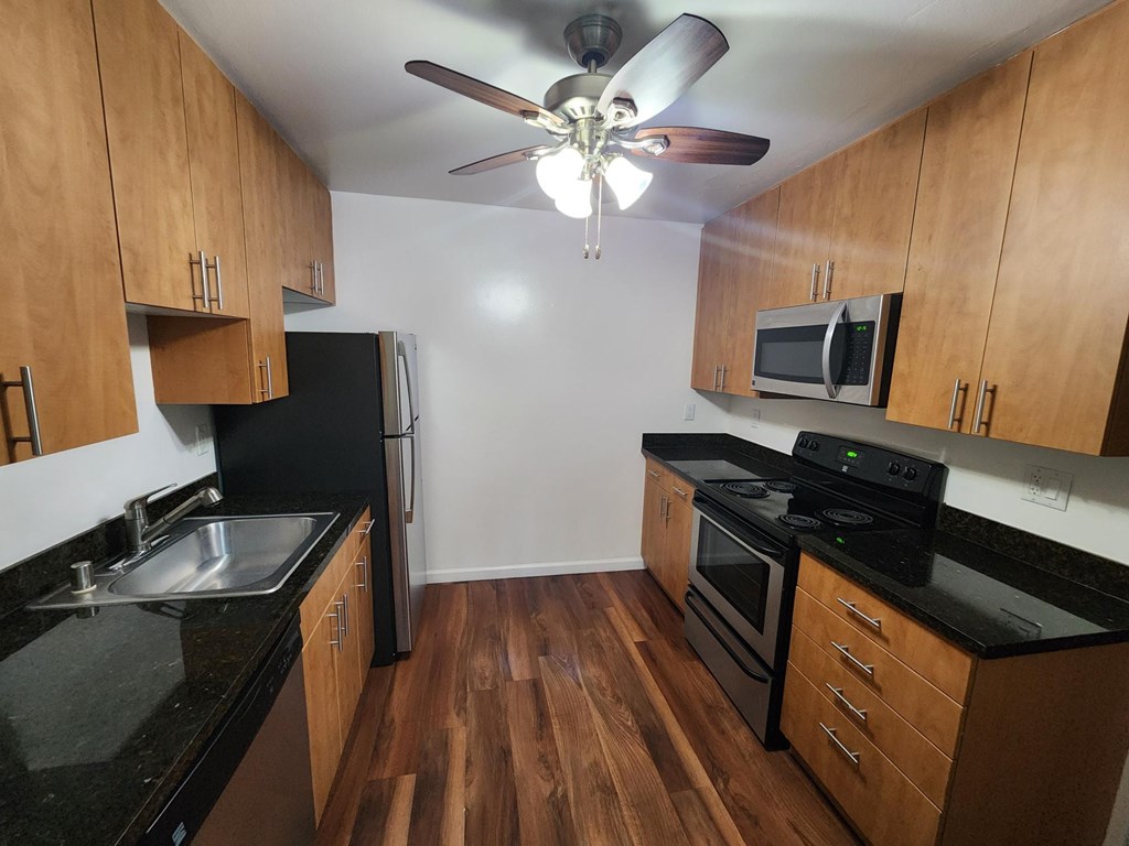 A kitchen with wooden cabinets and black countertops.