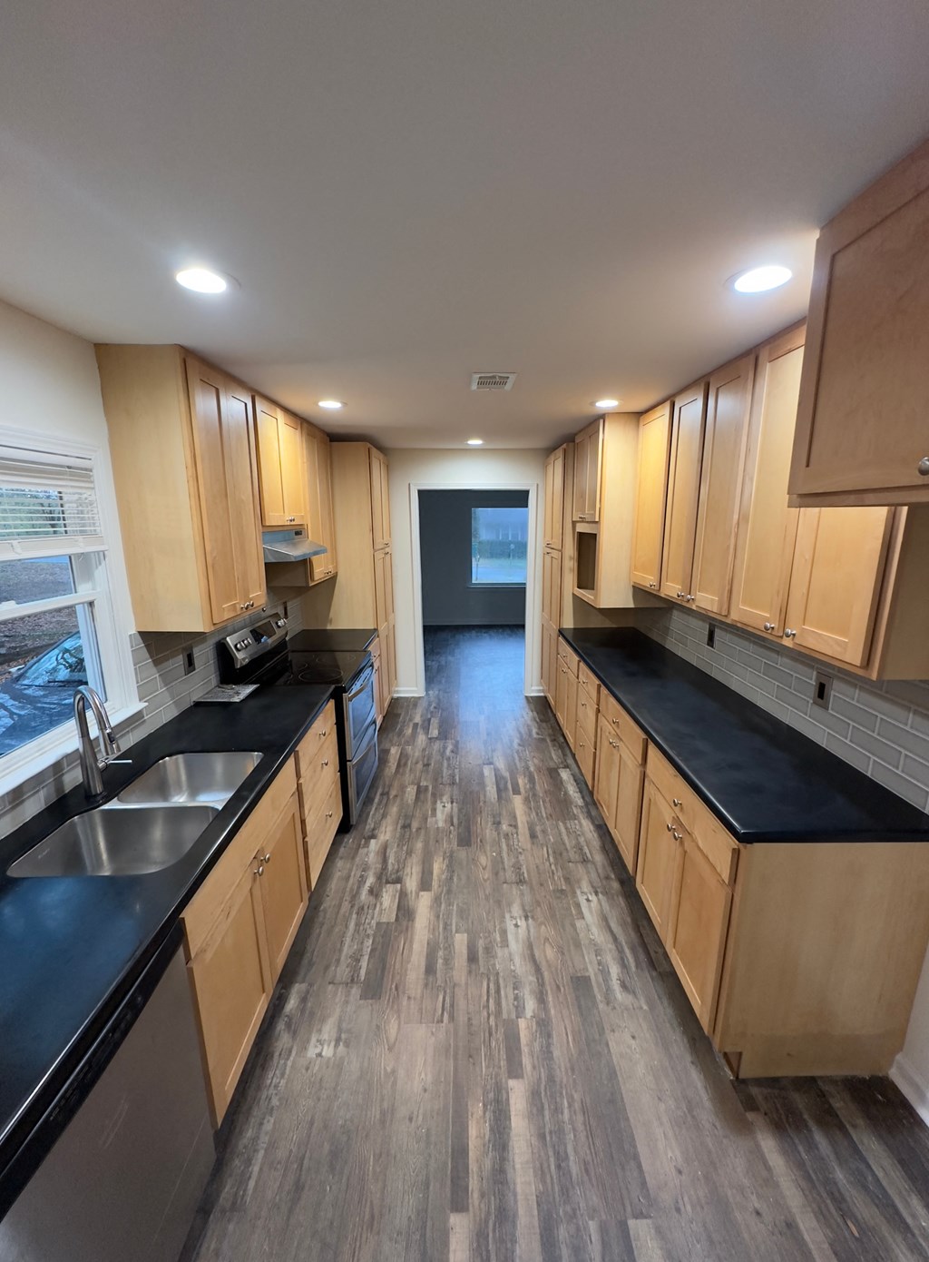 A kitchen with wooden cabinets and black countertops.