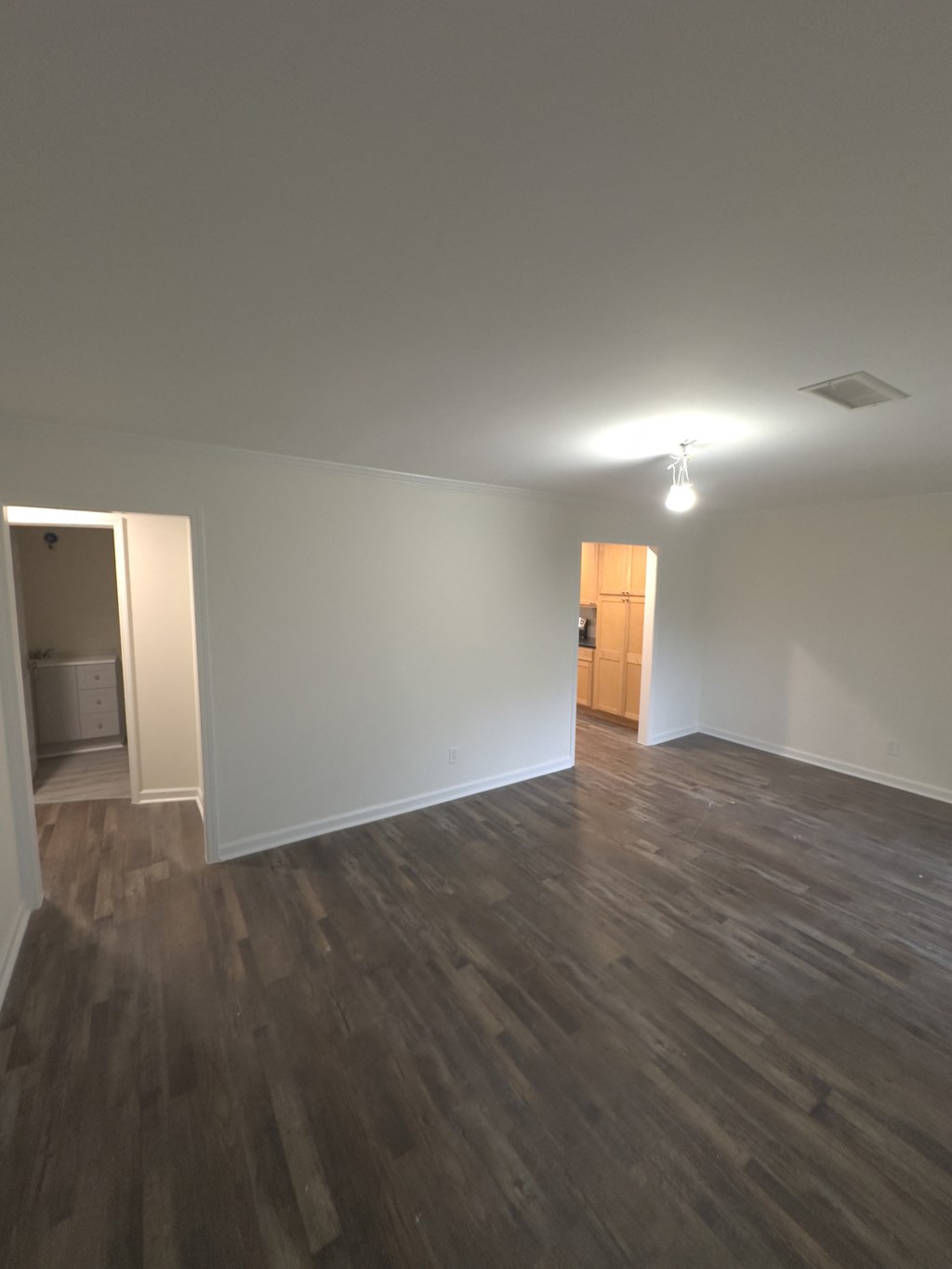 A room with wooden floors and a door in the background.
