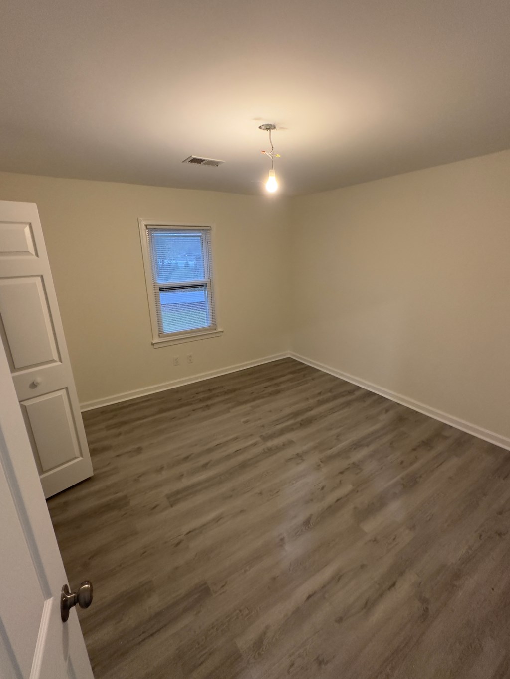 A room with a window and wooden flooring.