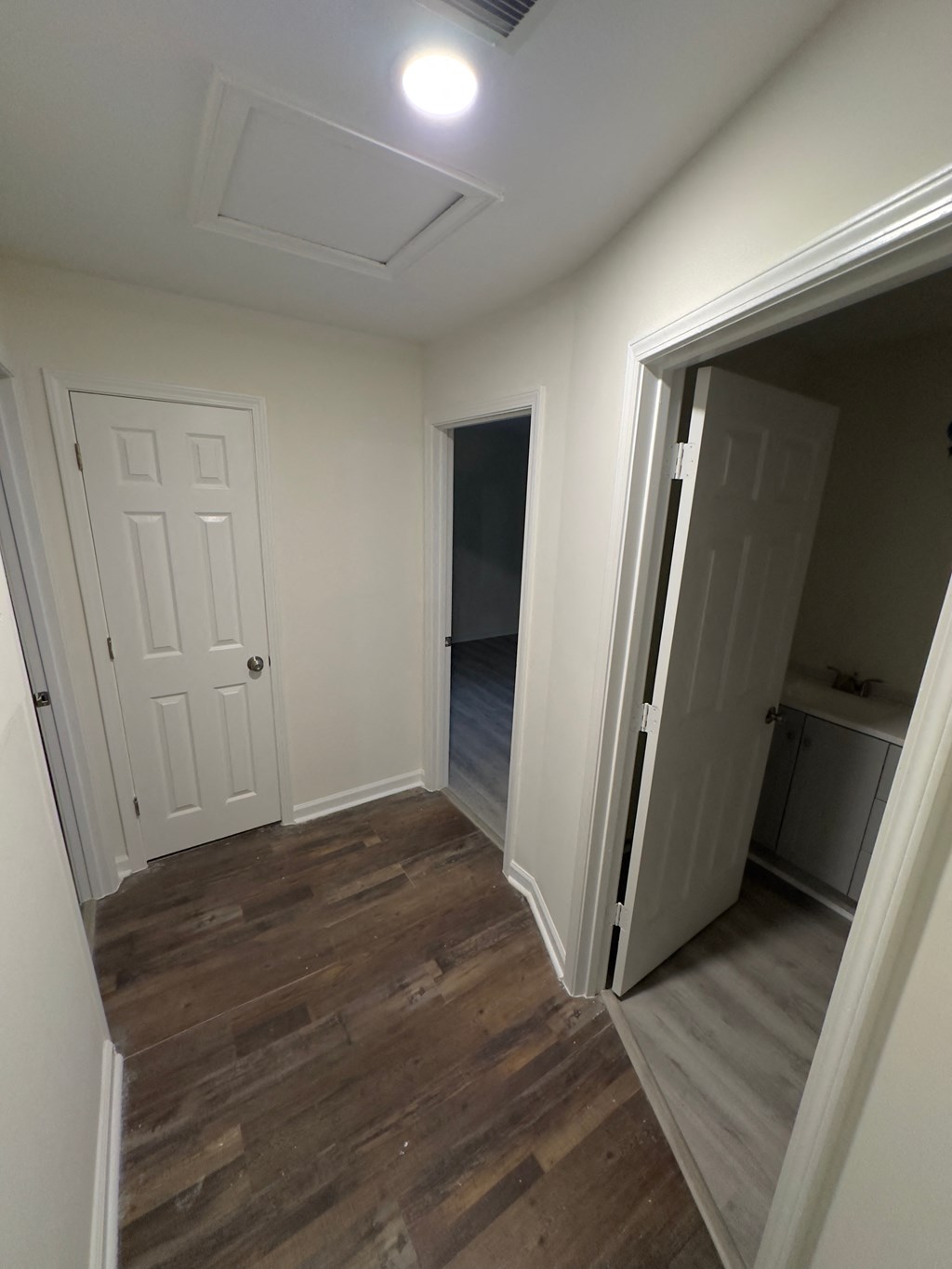 A room with a white door and a wooden floor.