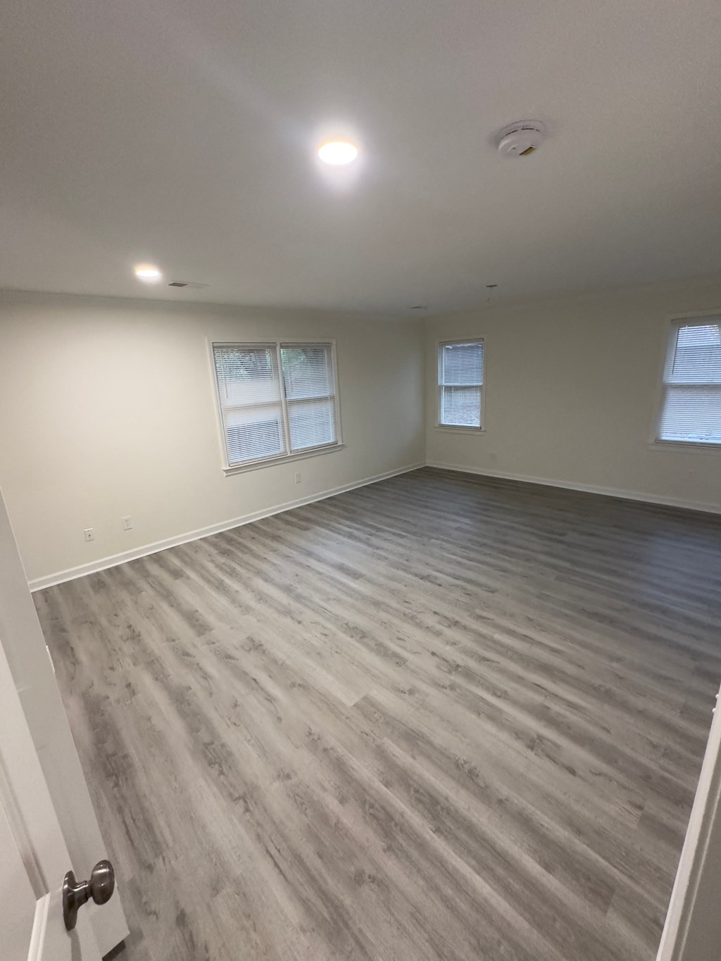 A room with a wooden floor and two windows.