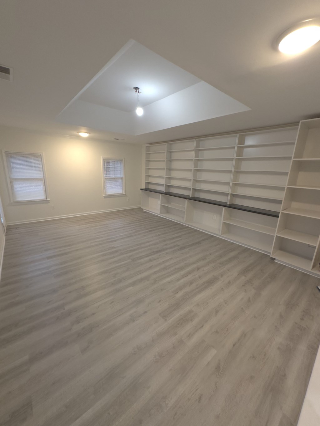A room with wooden flooring and shelving units.