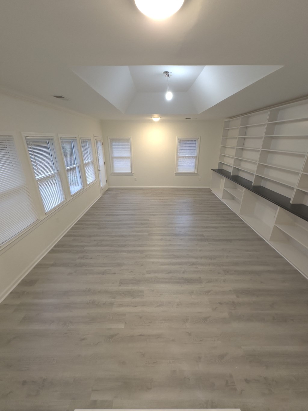 A long, empty room with wooden floors and white walls.