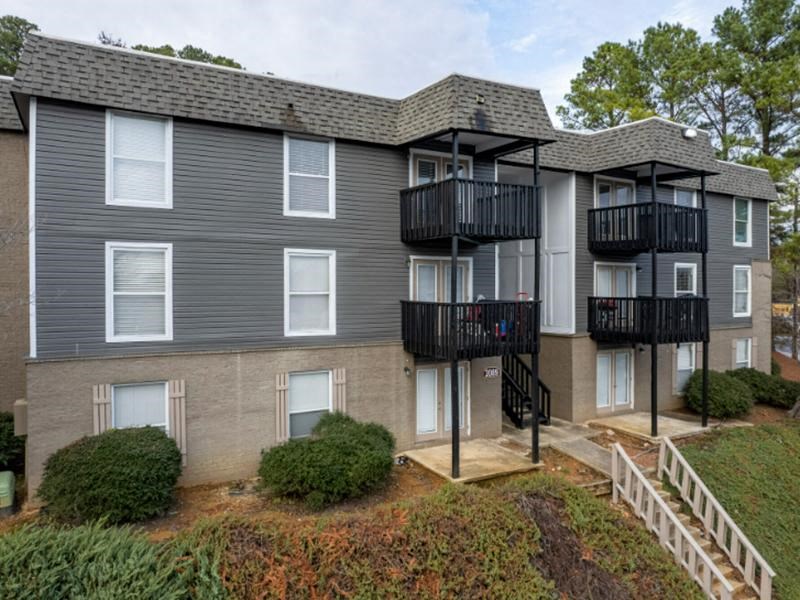 A grey apartment building with black railings and white windows.