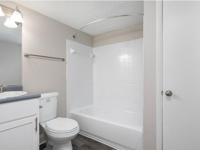 A white toilet sits next to a white bathtub in a small bathroom.