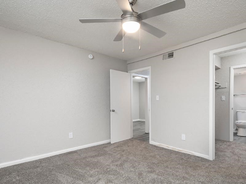 A room with a ceiling fan and carpeted floor.