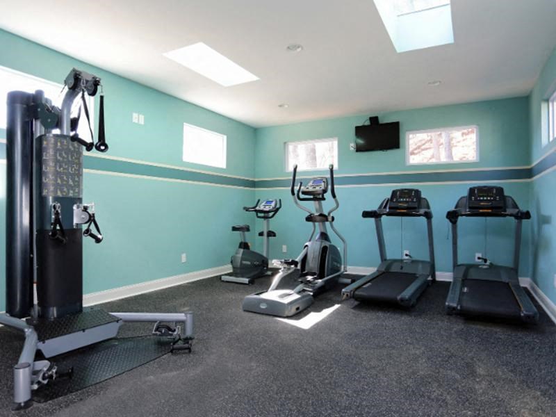 A home gym with a variety of equipment including treadmills, elliptical machines, and a weight bench.