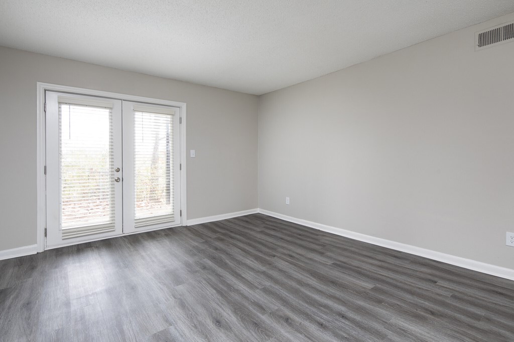 A room with a sliding glass door and wood flooring.