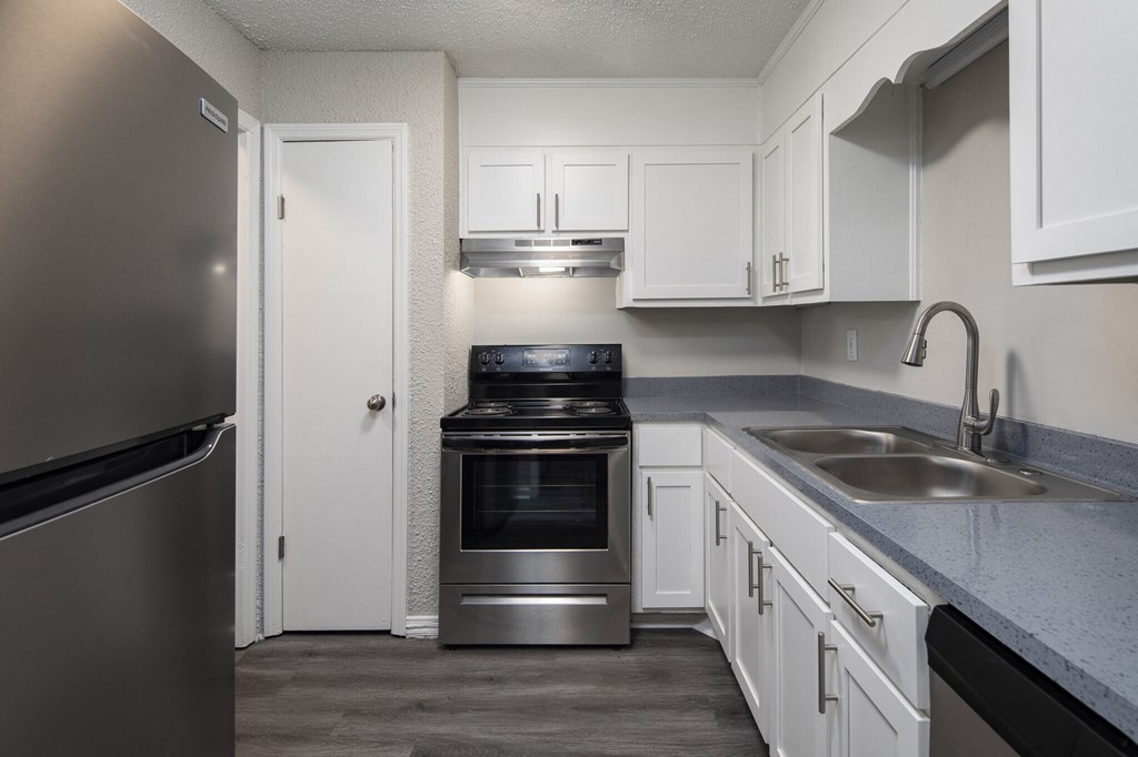 A kitchen with a refrigerator, oven, and sink.