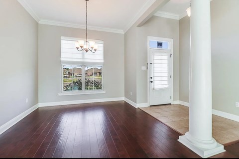 A room with a white door and a chandelier hanging from the ceiling.
