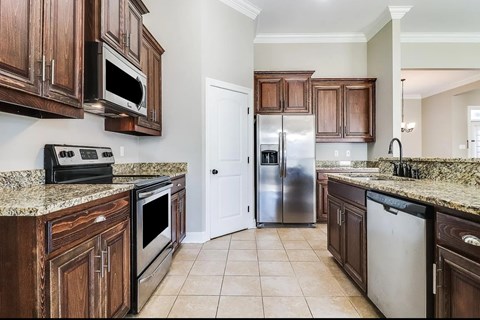 A kitchen with brown cabinets and a granite countertop.