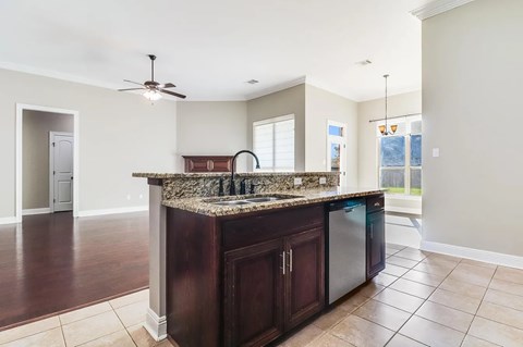 A kitchen with a granite countertop and dark wood cabinets.