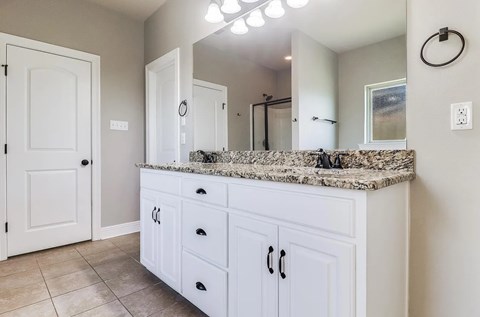 A bathroom with a marble countertop and white cabinets.