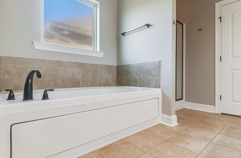A bathroom with a large tub and a window showing a field.