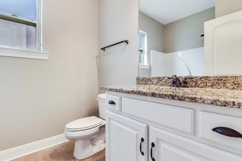 A bathroom with a toilet, sink, and a window.