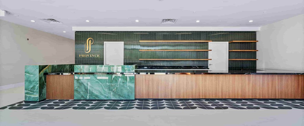 A reception area with a green marble wall and a wooden counter.