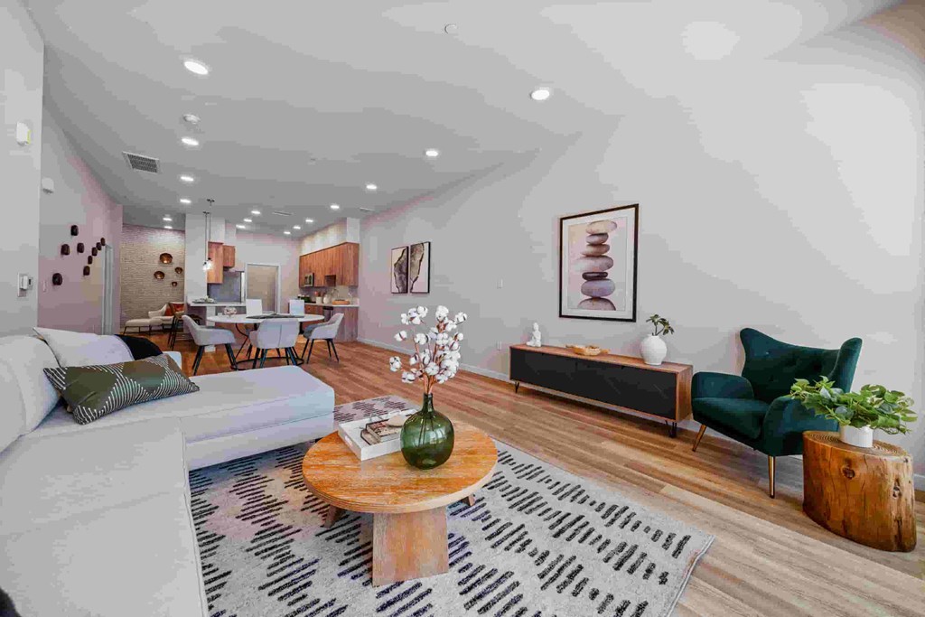 A living room with a white sofa, a wooden coffee table, and a green armchair.