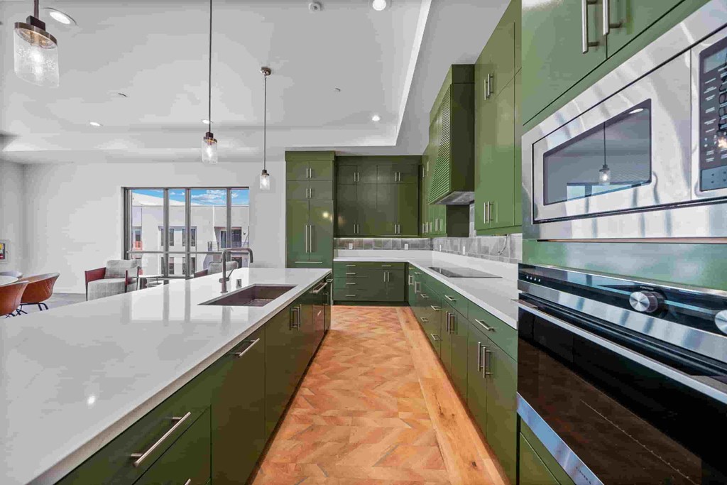 A modern kitchen with green cabinets and a white countertop.