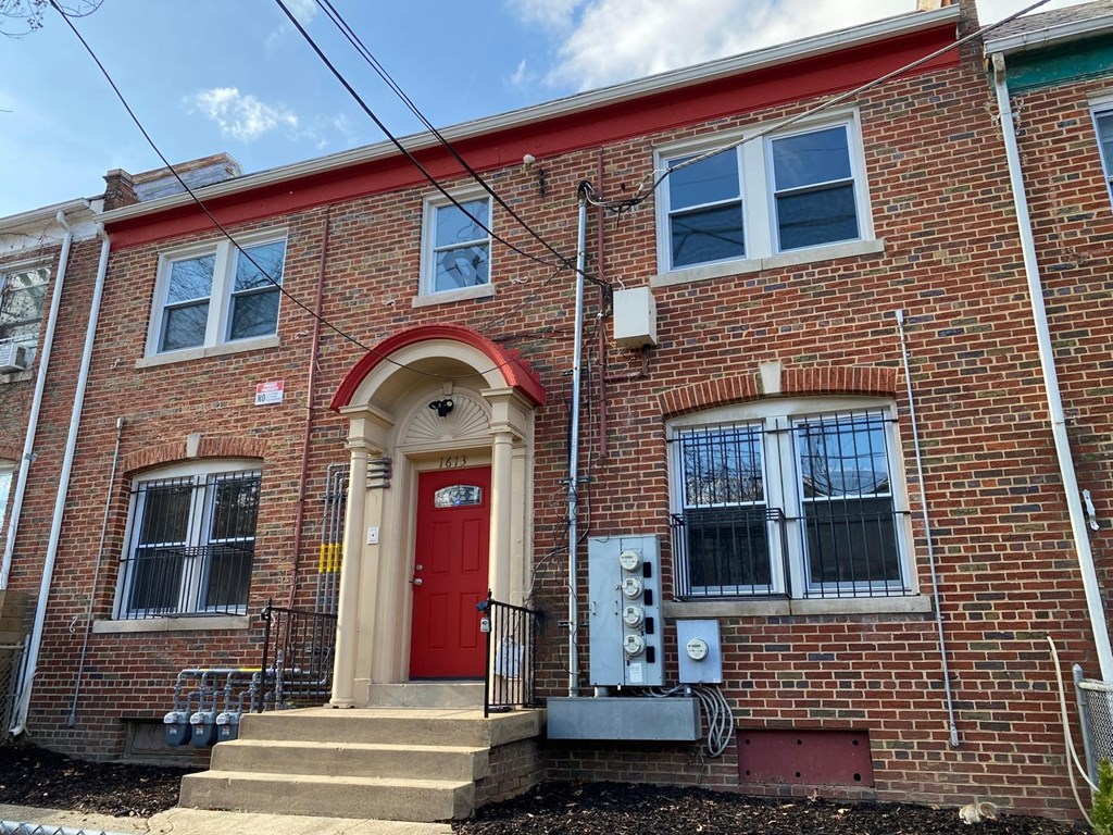 A red brick house with a red door and a small porch.