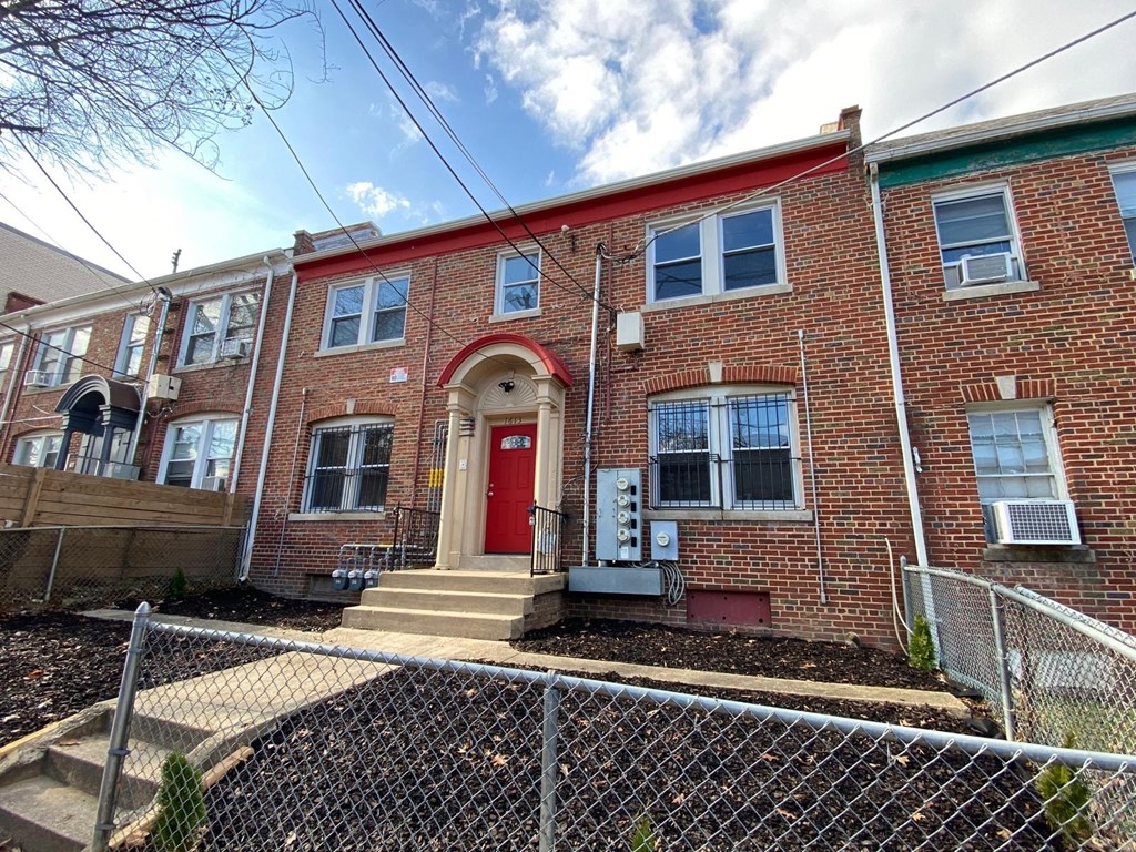 A red brick building with a red door and a small porch.