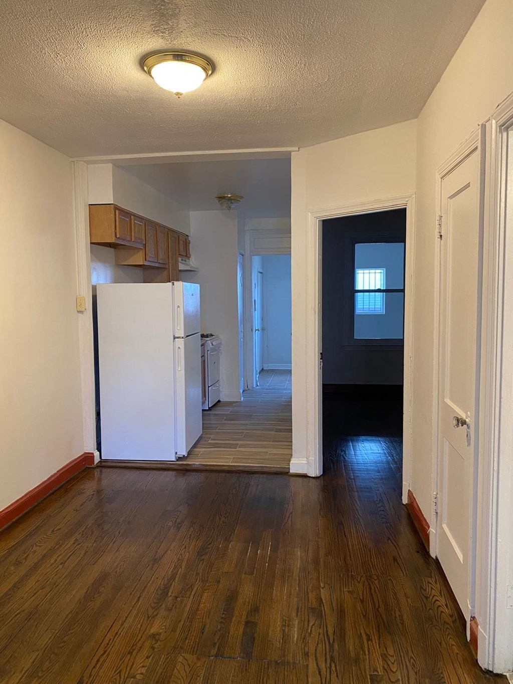 A kitchen with a white fridge and wooden floors.
