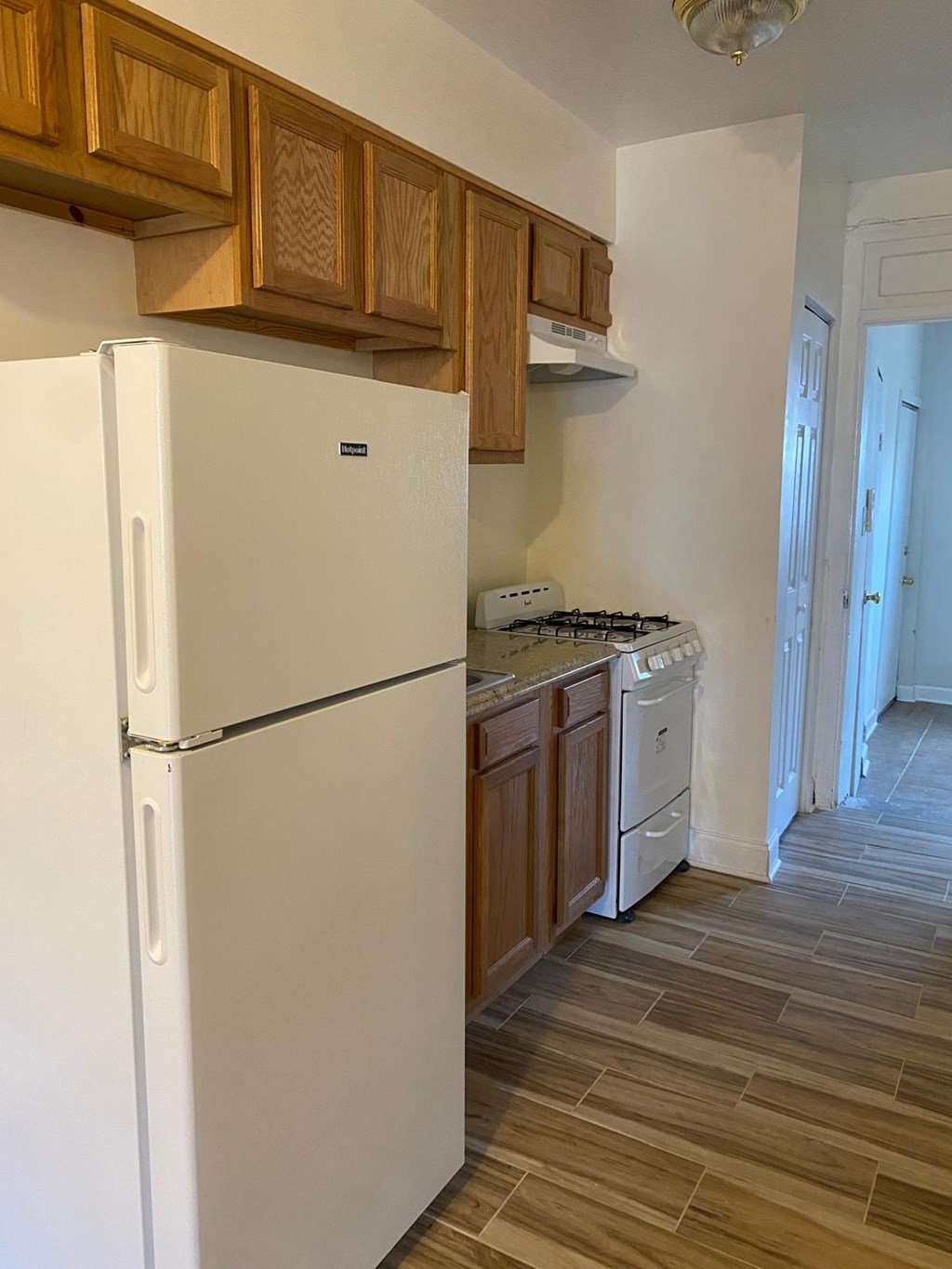 A white refrigerator in a kitchen with wooden cabinets.