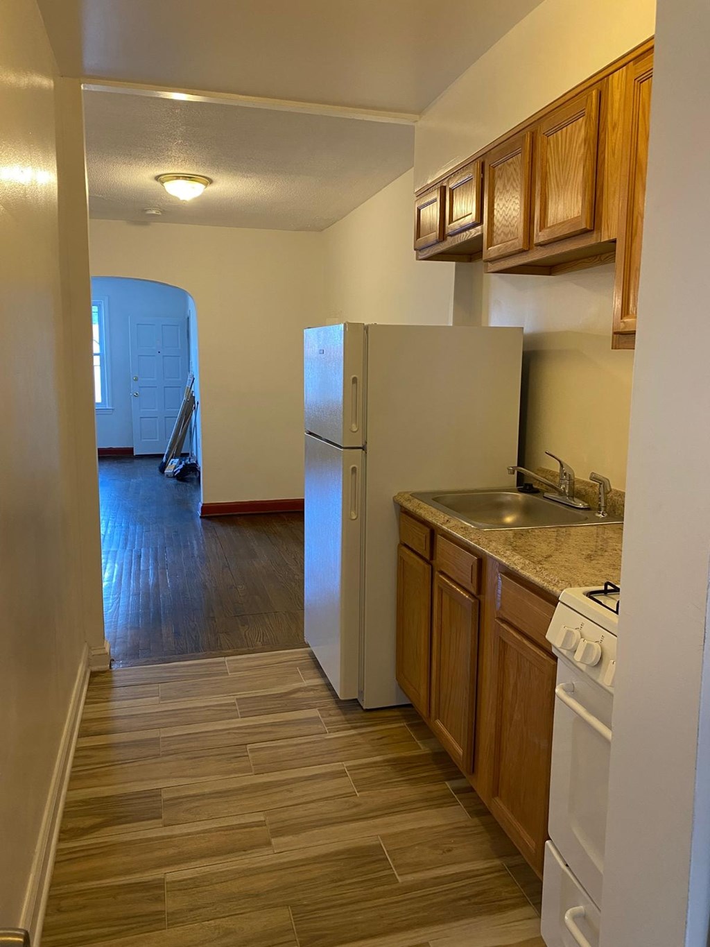 A kitchen with a white refrigerator and wooden cabinets.