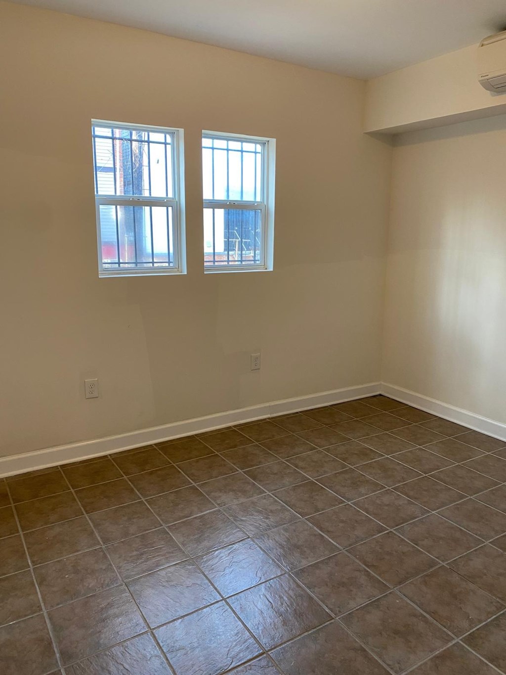 A room with tile flooring and two windows.