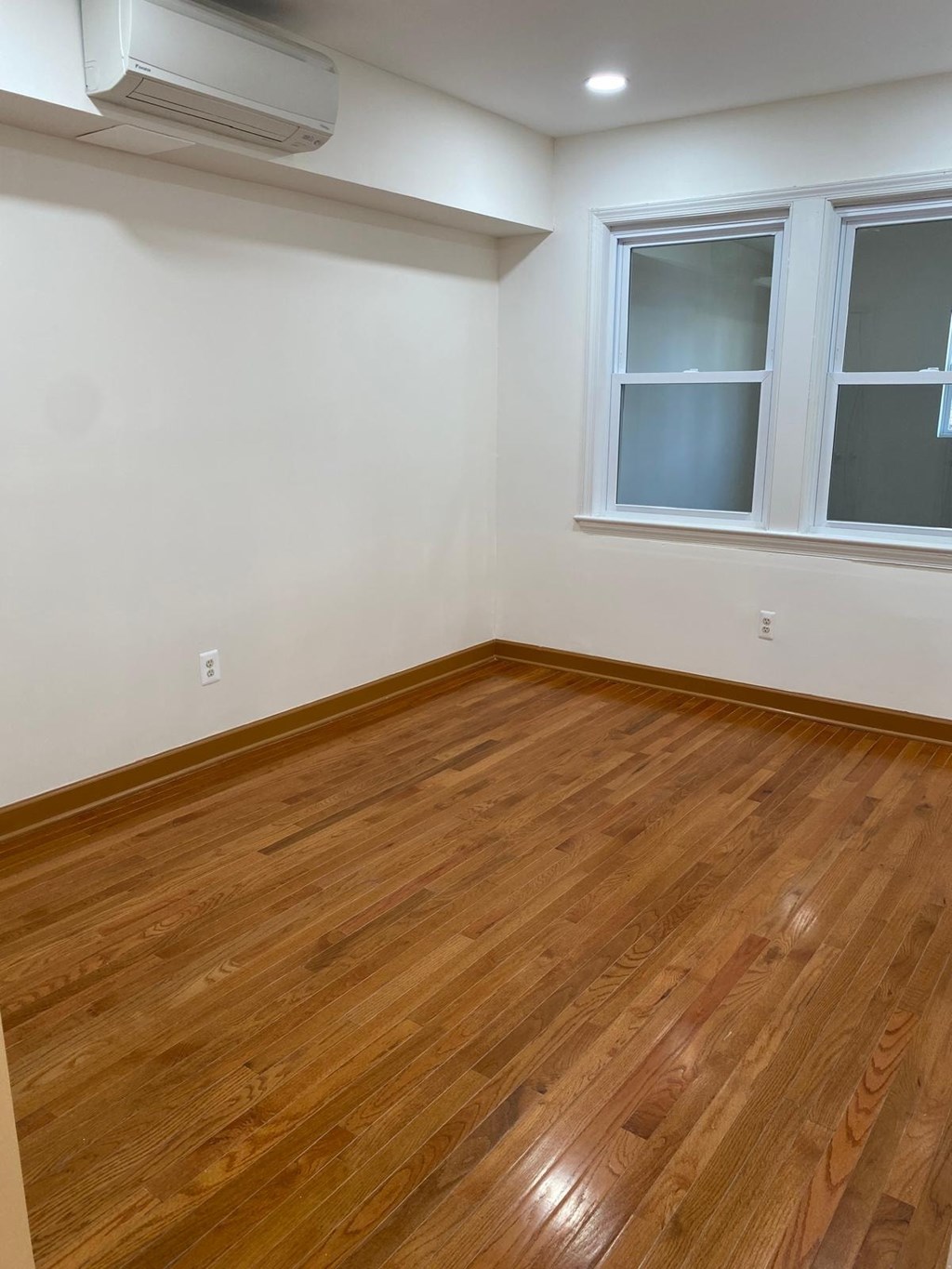 A room with a window and wooden flooring.