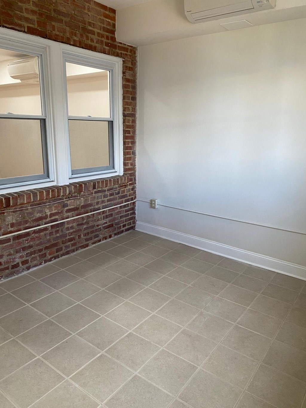 A room with a brick wall and a window.