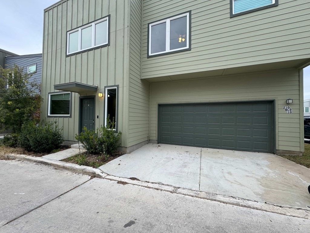 A two-story house with a garage door and a driveway.