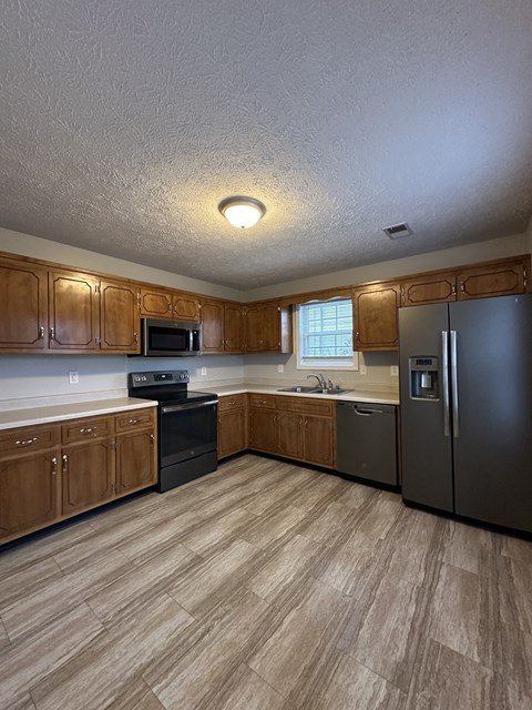 A kitchen with wooden cabinets and a black refrigerator.