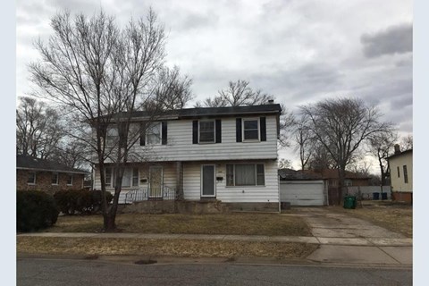 A two-story house with a white siding and a grey roof.
