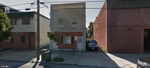 A street view of a residential area with a car parked on the sidewalk.