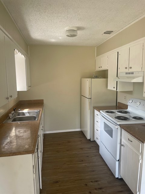 A kitchen with white cabinets and a white stove top oven.