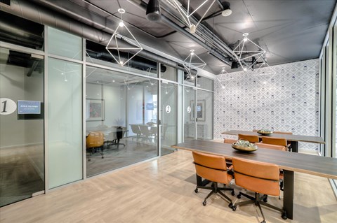 A conference room with glass walls and orange chairs.